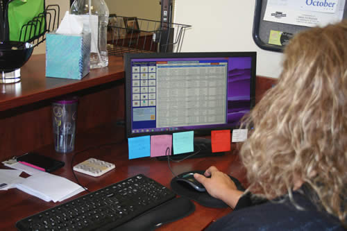 A woman uses MaidEasy's cleaning business software on her desktop computer in her office.