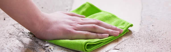 A cleaner wipes up a mess on the ground with a green towel.