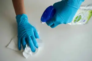 A cleaner cleans a table with some spray cleaner and a towel.